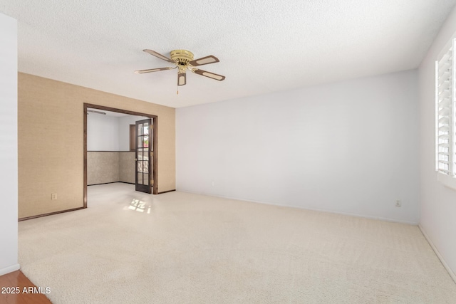 unfurnished room with ceiling fan, a healthy amount of sunlight, light carpet, and a textured ceiling