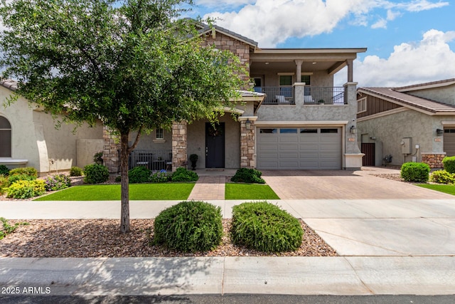 2605 S Quaintance St, Gilbert, AZ 85295 - view of front of house featuring a balcony, decorative driveway, stucco siding, a garage, and stone siding