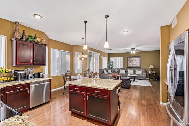 kitchen featuring a center island, light hardwood / wood-style flooring, decorative light fixtures, ceiling fan with notable chandelier, and appliances with stainless steel finishes