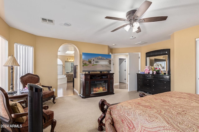 carpeted bedroom with ensuite bath and ceiling fan