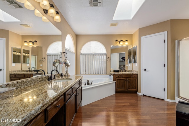 bathroom featuring a skylight, a bathtub, vanity, a textured ceiling, and wood-type flooring