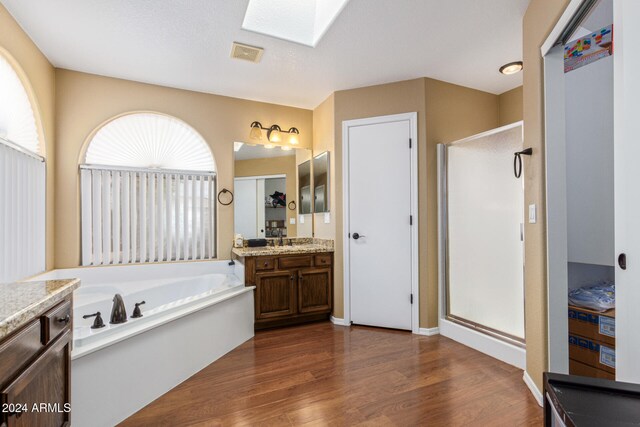 bathroom with separate shower and tub, a skylight, vanity, and hardwood / wood-style flooring