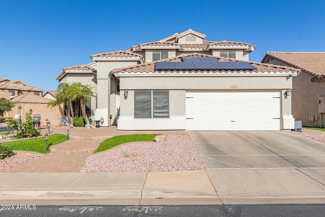 mediterranean / spanish-style home featuring solar panels and a garage