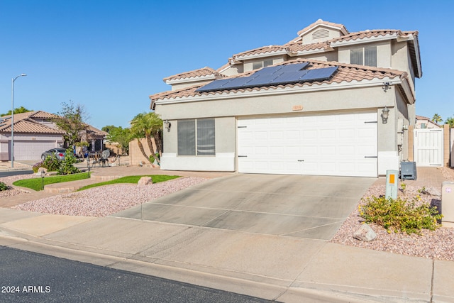 mediterranean / spanish-style house featuring a garage and solar panels