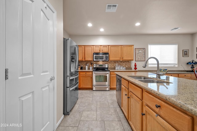 kitchen featuring light stone countertops, sink, tasteful backsplash, light tile patterned flooring, and appliances with stainless steel finishes