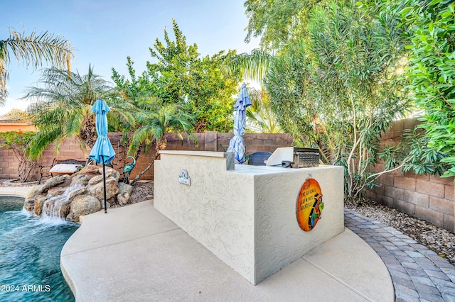 view of patio with pool water feature, area for grilling, and a fenced in pool