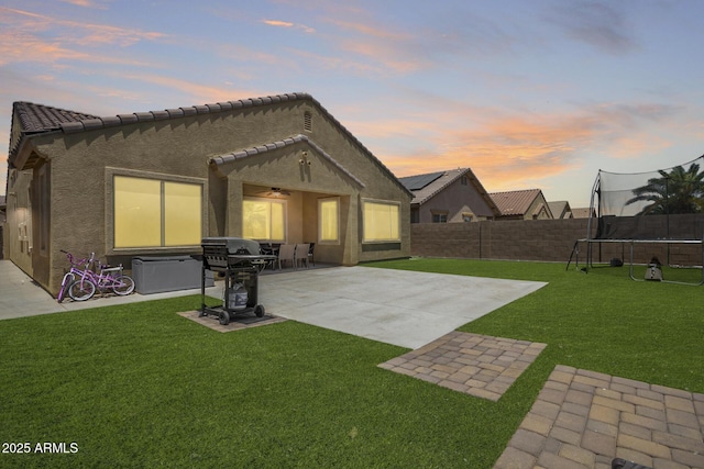 291 E Canyon Rock Rd, San Tan Valley, AZ 85143 - back of house featuring a tile roof, a fenced backyard, a trampoline, a ceiling fan, and a patio