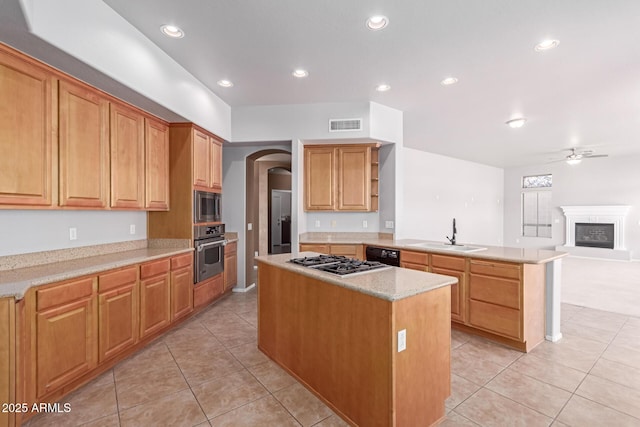 kitchen with a kitchen island, a peninsula, arched walkways, a sink, and appliances with stainless steel finishes