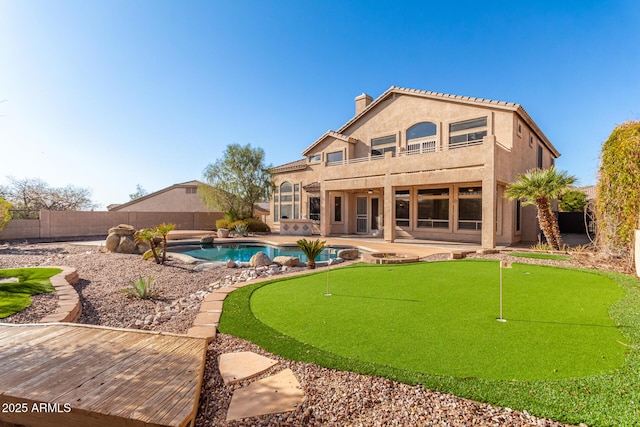 rear view of property featuring stucco siding, a fenced backyard, a fenced in pool, a balcony, and a patio area