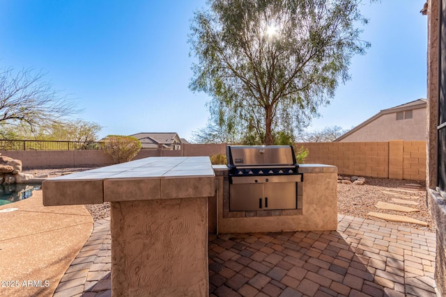 view of patio / terrace featuring exterior kitchen, area for grilling, and a fenced backyard