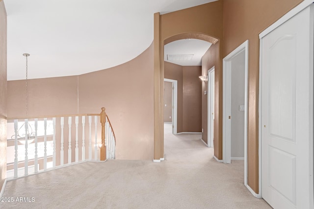 hallway with visible vents, an upstairs landing, arched walkways, carpet, and baseboards