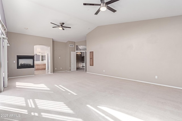 unfurnished living room featuring baseboards, arched walkways, a ceiling fan, and vaulted ceiling