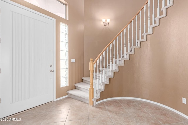 foyer with tile patterned flooring, plenty of natural light, stairs, and baseboards