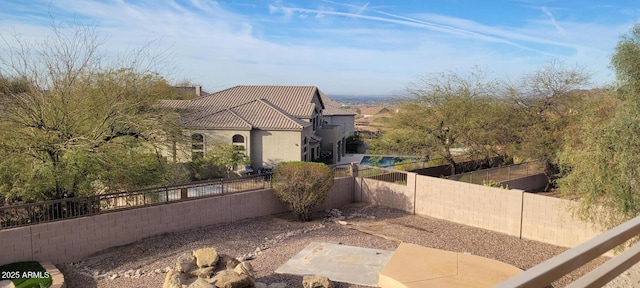 view of side of property featuring a tile roof, a fenced backyard, and stucco siding