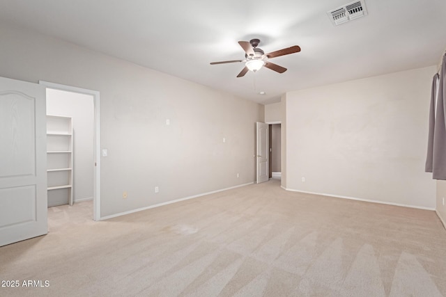 unfurnished room with ceiling fan, light colored carpet, visible vents, and baseboards