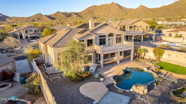 rear view of property with stucco siding, a patio, a fenced backyard, a mountain view, and a balcony