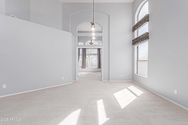 spare room featuring a high ceiling, carpet, and baseboards