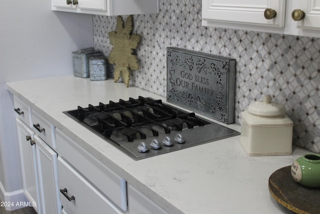 kitchen with white cabinets, black gas stovetop, backsplash, and light stone countertops