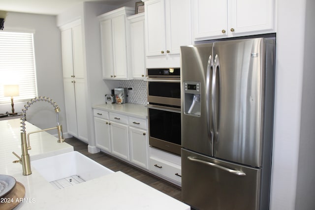 kitchen featuring appliances with stainless steel finishes, sink, tasteful backsplash, white cabinetry, and dark hardwood / wood-style flooring