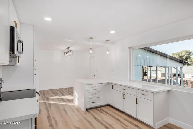 kitchen with kitchen peninsula, white cabinets, pendant lighting, and light wood-type flooring