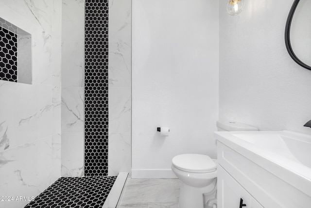 bathroom featuring a tile shower, vanity, and toilet