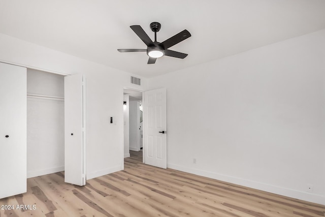 unfurnished bedroom featuring ceiling fan, a closet, and light wood-type flooring