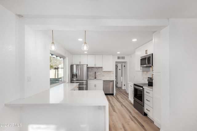 kitchen featuring kitchen peninsula, white cabinetry, stainless steel appliances, and decorative light fixtures