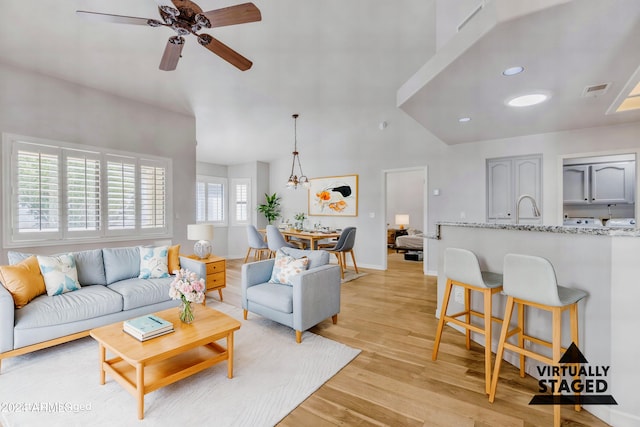 living room with ceiling fan, sink, and light wood-type flooring