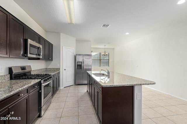 kitchen featuring hanging light fixtures, sink, light tile patterned floors, an island with sink, and appliances with stainless steel finishes