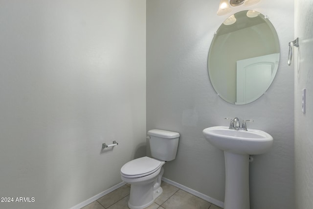 bathroom with toilet, sink, and tile patterned flooring