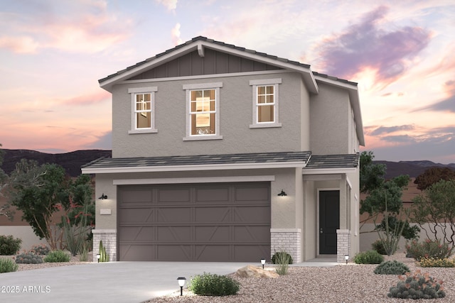 17373 W Jessie Ln, Surprise, AZ 85387 - view of front of house with concrete driveway, an attached garage, board and batten siding, a mountain view, and stone siding