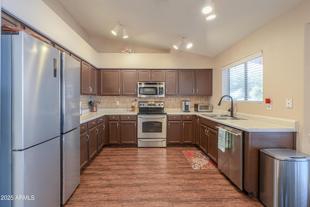 kitchen featuring tasteful backsplash, lofted ceiling, appliances with stainless steel finishes, light countertops, and a sink