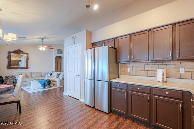 kitchen with freestanding refrigerator, backsplash, light countertops, and arched walkways