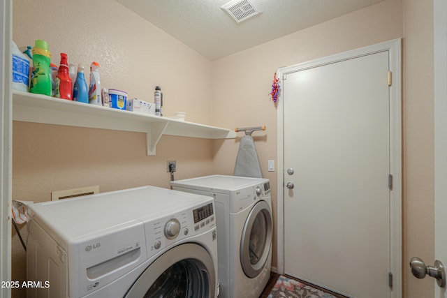 washroom featuring laundry area, visible vents, a textured ceiling, and washing machine and clothes dryer