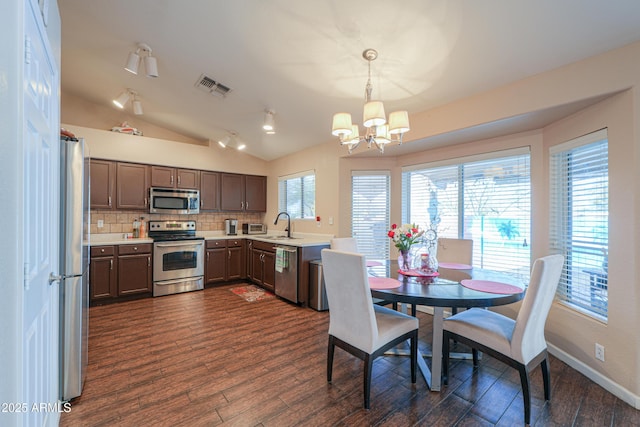 kitchen with dark wood-style flooring, visible vents, light countertops, appliances with stainless steel finishes, and decorative light fixtures