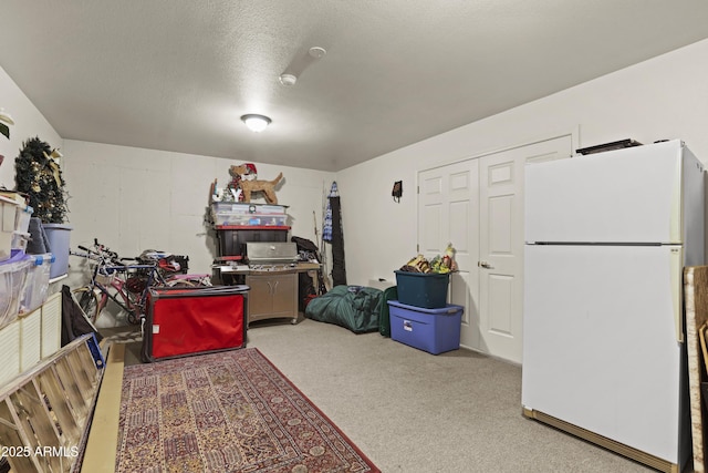 interior space with white refrigerator, light colored carpet, and a textured ceiling