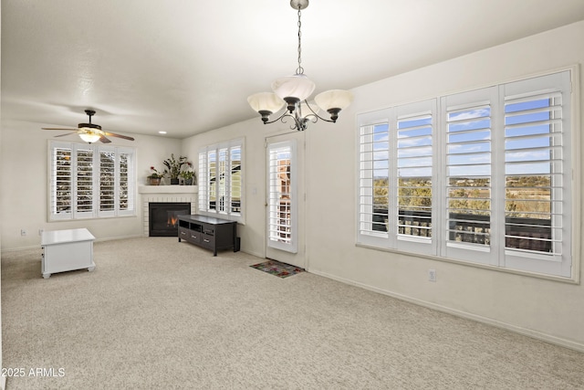 unfurnished living room featuring a fireplace, ceiling fan with notable chandelier, and carpet floors