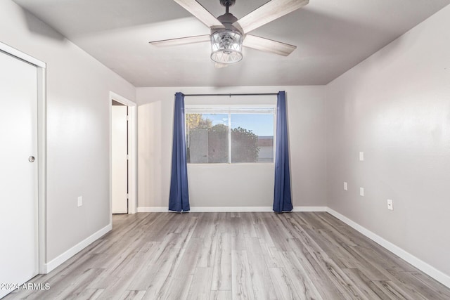 empty room with light wood-style flooring, a ceiling fan, and baseboards
