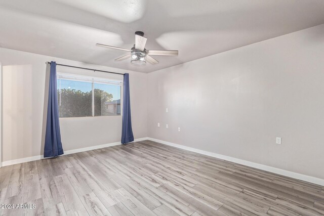 unfurnished room featuring a ceiling fan, wood finished floors, and baseboards