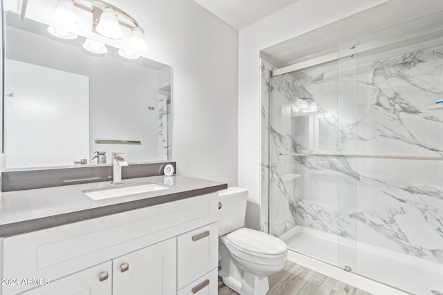 full bath featuring a marble finish shower, toilet, wood finished floors, and vanity