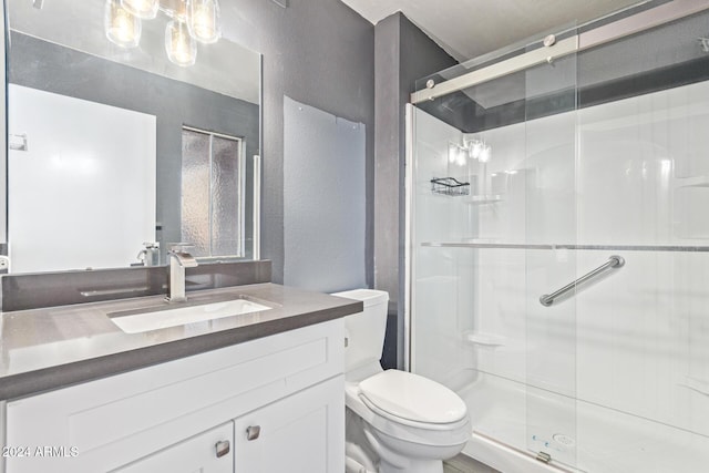full bathroom featuring vanity, toilet, a textured wall, and a stall shower
