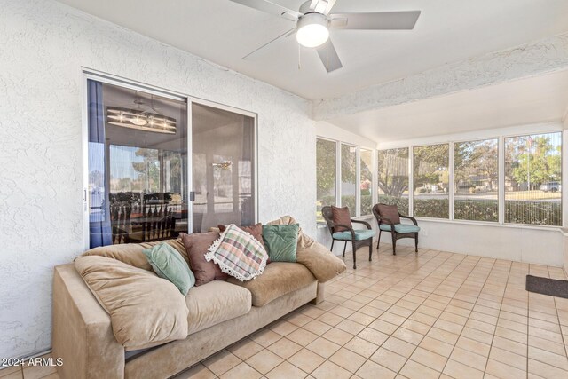 sunroom / solarium featuring an outdoor living space, tile patterned flooring, a ceiling fan, and a textured wall