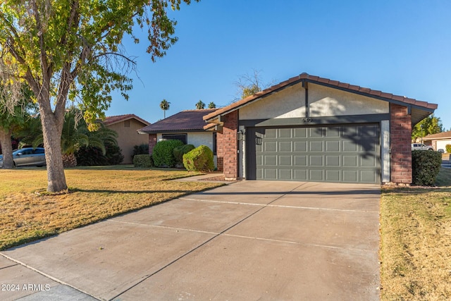 ranch-style home featuring brick siding, a garage, driveway, and a front lawn