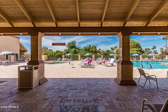 view of patio with a community pool and fence