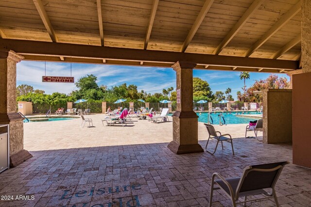 view of patio with a community pool and fence