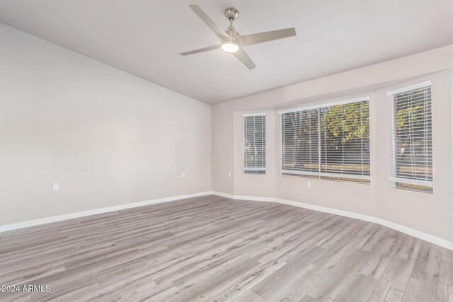 empty room featuring light wood-style flooring, baseboards, lofted ceiling, and ceiling fan