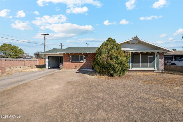 single story home with a garage, brick siding, driveway, and fence