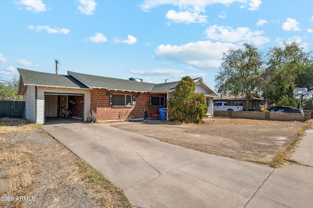 single story home featuring concrete driveway, brick siding, fence, and an attached garage