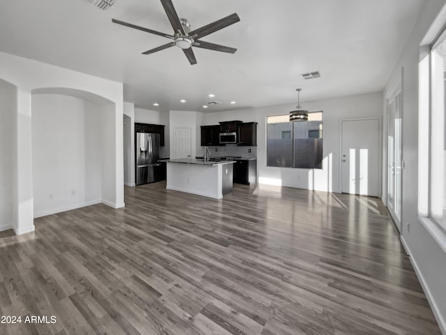 unfurnished living room featuring ceiling fan with notable chandelier, sink, and dark hardwood / wood-style flooring