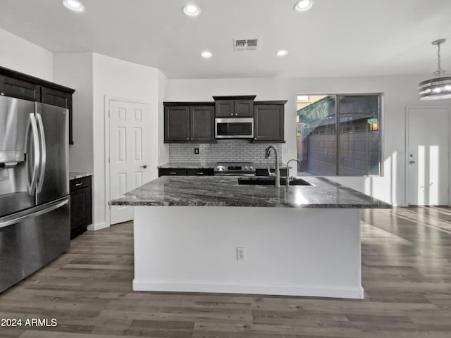 kitchen featuring dark stone countertops, appliances with stainless steel finishes, dark hardwood / wood-style floors, and sink